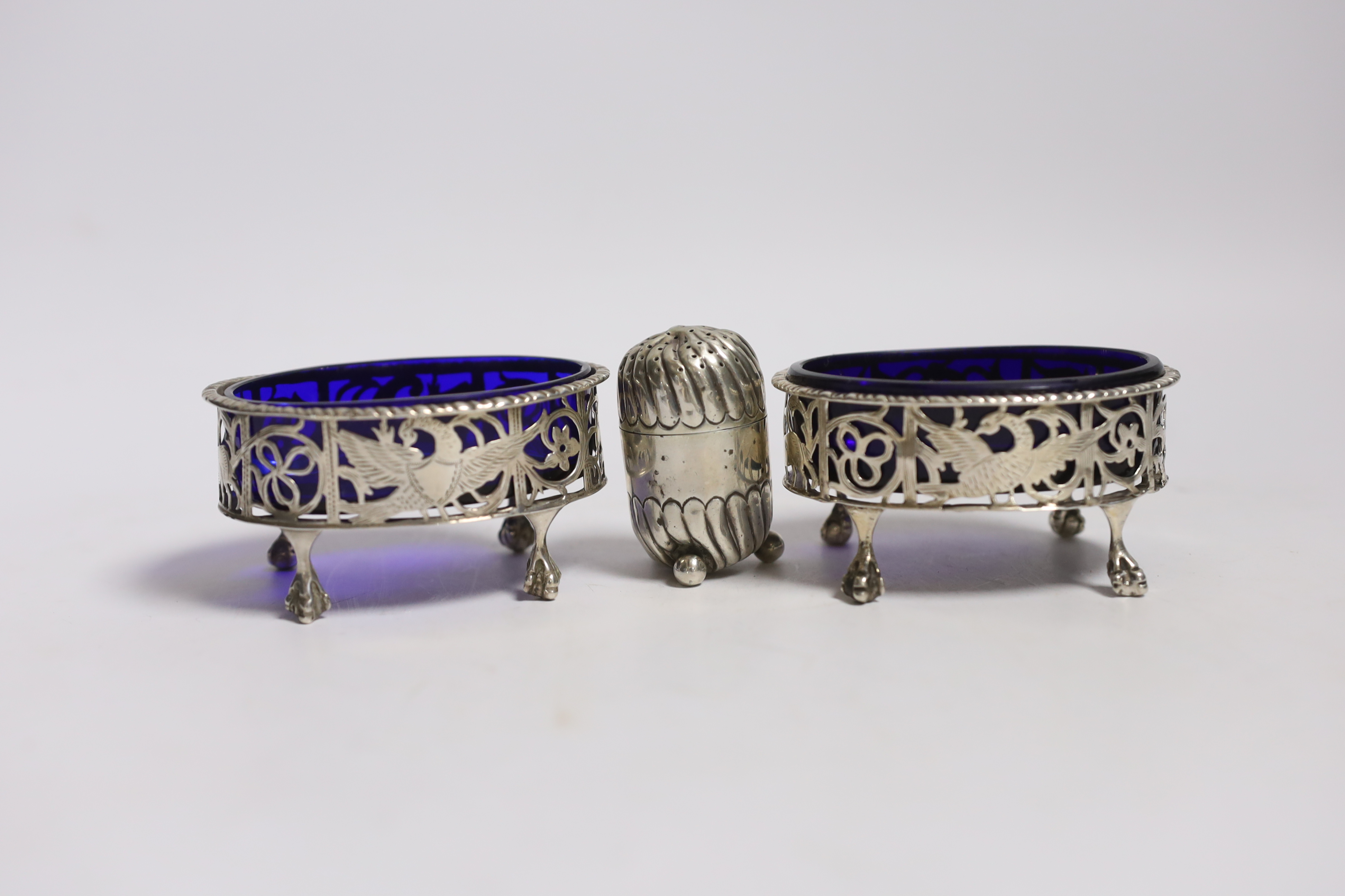 A pair of Edwardian pierced silver oval salts, Charles Stuart Harris, London, 1901/2, 82mm(a.f.), with blue glass liner and later associated spoons, together with a silver pepperette.